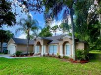 Charming single-story home with a well-maintained lawn, mature landscaping, and a welcoming entrance framed by stately columns at 3275 Phonetia Dr, Deltona, FL 32738