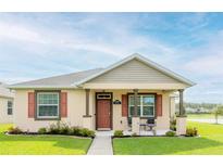 Inviting single-story home featuring a well-manicured lawn, a cozy porch with seating, and charming curb appeal at 3365 Meleto Blvd, New Smyrna Beach, FL 32168