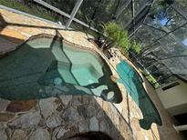 A unique, private pool and spa enclosed in screened enclosure, features rock accents, and lush landscaping at 1780 Otisco Way, Winter Springs, FL 32708
