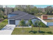 Modern home with dark gray roof and white exterior, featuring a two-car garage at 1428 Willow Oak Dr, Edgewater, FL 32132