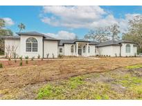 White two-story house with a gray roof, arched windows, and walkway at 1371 Melonie Trl, New Smyrna Beach, FL 32168