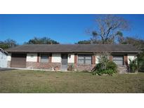 Ranch-style home with brown brick and vinyl siding, spacious lawn, and mature trees at 2325 Date Palm Dr, Edgewater, FL 32141