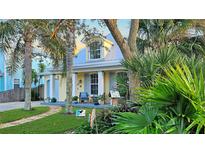 Charming yellow house with gray metal roof, front porch, and lush landscaping at 915 Maple St, New Smyrna Beach, FL 32169