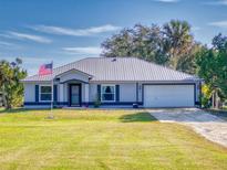 Single-story home with metal roof, attached garage, and landscaped lawn at 977 Bay Dr, New Smyrna Beach, FL 32168