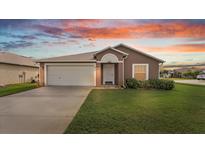 House exterior view at dusk, featuring a two-car garage and well-manicured lawn at 230 Oak Branch Dr, Edgewater, FL 32141