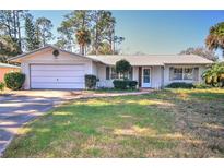 Ranch-style home with white brick exterior, attached garage, and mature landscaping at 1120 Marcel St, New Smyrna Beach, FL 32168