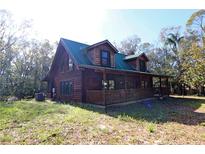 Rustic log cabin with a green metal roof and a spacious porch at 187 N Samsula Dr, New Smyrna Beach, FL 32168