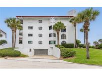 White building exterior with palm trees and a garage at 3001 S Atlantic Ave # 503, New Smyrna Beach, FL 32169