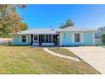 Light teal house with metal roof, walkway, and well-maintained lawn at 3015 Queen Palm Dr, Edgewater, FL 32141