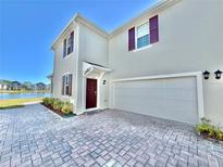 Two-story house with attached garage, paver driveway, and a pond view at 3035 Meleto Blvd, New Smyrna Beach, FL 32168