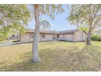 Tan house with a large front yard and mature trees at 3103 Royal Palm Dr, Edgewater, FL 32141