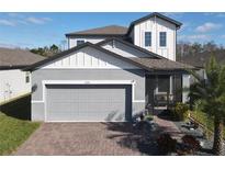 Two-story house with gray siding, gray roof, and a brick paver driveway at 3133 Crab Trap Dr, New Smyrna Beach, FL 32168