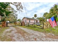 Pink house with a black metal gate and a wooden fence at 388 N Glencoe Rd, New Smyrna Beach, FL 32168