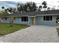 Ranch style home with a light blue exterior, gravel driveway, and well-manicured lawn at 795 Biro Dr, Port Orange, FL 32129