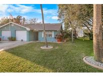 Light teal home with a well-manicured lawn and mature trees at 1253 Harbour Point Dr, Port Orange, FL 32127