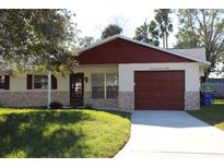 House exterior featuring a red roof, stone accents, and a well-maintained lawn at 2408 Victory Palm Dr, Edgewater, FL 32141