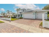 Two-story light teal home with a large driveway, white picket fence, and mature landscaping at 2817 Bay Side Dr, New Smyrna Beach, FL 32168