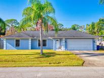 Cute light blue house with a palm tree and a two-car garage at 3220 Tamarind Dr, Edgewater, FL 32141