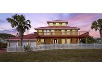 Two-story house with red metal roof, white fence, and palm trees at 3726 S Atlantic Ave, New Smyrna Beach, FL 32169