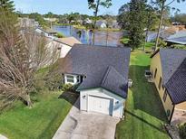 Aerial view of a single-story house with a garage, and a lake in the background at 813 Pine Shores Cir, New Smyrna Beach, FL 32168