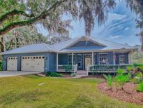 Charming blue house with a metal roof, two-car garage, and a spacious front porch at 1004 Flying M Ct, Edgewater, FL 32132