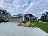 Gray house with attached garage, stone walkway, and landscaped lawn at 1104 Red Maple Way, New Smyrna Beach, FL 32168