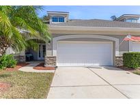 Exterior view of a villa with a two-car garage, stone accents, and palm trees at 1938 Turnbull Lakes Dr, New Smyrna Beach, FL 32168