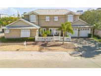 Tan two-story house with white shutters, white picket fence, and palm trees at 201 S Cooper St, New Smyrna Beach, FL 32169