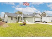 Newly built home with green exterior, two car garage, and well-manicured lawn at 2717 Needle Palm Dr, Edgewater, FL 32141