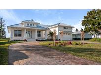 White two-story house with gray metal roof, paved driveway, and landscaped yard at 437 S Peninsula Ave, New Smyrna Beach, FL 32169