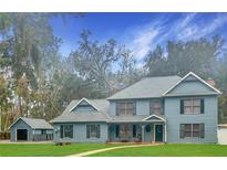 Two-story light blue house with a detached garage and landscaped lawn at 472 Wildwood Dr, New Smyrna Beach, FL 32168