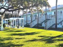 Light teal building with multiple units, stairs, and a grassy courtyard at 541 S Peninsula Ave # A03, New Smyrna Beach, FL 32169