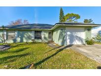 Ranch style home with a green exterior, white garage door, and well-maintained lawn at 84 Tumbler Dr, Port Orange, FL 32129