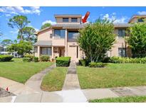 Charming two-story townhouse with manicured lawn, mature trees, and a welcoming walkway to the front door at 105 Wood Duck Cir # 1C, Daytona Beach, FL 32119