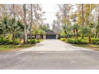 Charming brick home featuring mature landscaping, an extended driveway, and attached two-car garage at 2232 Swoope Dr, New Smyrna Beach, FL 32168