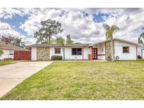 Charming single-story home featuring stone accents, mature trees, and a well-manicured lawn at 2712 Queen Palm Dr, Edgewater, FL 32141