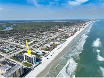 Stunning aerial view of beachfront condo, sparkling pool, and sandy beach on a sunny day at 3405 S Atlantic Ave # 501, New Smyrna Beach, FL 32169