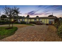 Charming single-story home with a brick driveway, manicured lawn, and well-lit exterior at 4650 Saxon Dr, New Smyrna Beach, FL 32169