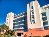 Building exterior showcasing multiple floors with balconies, palm trees and parking garage entrance at 5300 S Atlantic Ave # 3-504, New Smyrna Beach, FL 32169