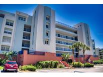 Multi-story building featuring multiple balconies and a manicured landscape with palm trees on a bright, sunny day at 5300 S Atlantic Ave # 3-504, New Smyrna Beach, FL 32169
