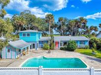 Beautiful pool area with turquoise water and an attached accessory building under a bright blue sky at 634 N Riverside Dr, New Smyrna Beach, FL 32168