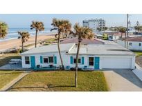 Charming beach home featuring turquoise shutters, a one-car garage, and swaying palm trees with ocean views at 8 Ocean Dr, Ormond Beach, FL 32176