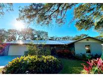 Ranch-style home with metal roof, landscaping, and a two-car garage at 832 S Cooper St, New Smyrna Beach, FL 32169