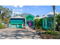 Unique home with bright turquoise exterior, two-car garage, and vibrant pink front door at 61 E Bayshore Dr, Port Orange, FL 32127