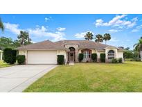 Charming single-story home featuring a well-manicured lawn, mature landscaping, and a two-car garage at 6182 Knotty Pine Ct, Port Orange, FL 32127