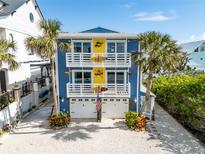 Coastal home featuring palm trees, white railings, surfboards and a three-car garage in a beach community at 6531 Turtlemound Rd, New Smyrna Beach, FL 32169