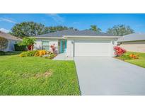 Charming single-story home with well-manicured lawn, colorful landscaping, and a bright blue front door at 662 Wellesley Ct, New Smyrna Beach, FL 32168