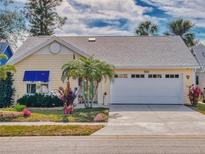 Charming yellow single-story home featuring a well-manicured lawn and an attached two-car garage at 751 Pine Shores Cir, New Smyrna Beach, FL 32168