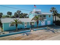 Charming blue two-story home with a rooftop deck, complemented by palm trees and beachy surroundings at 923 Locust St, New Smyrna Beach, FL 32169