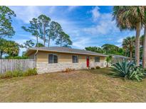 Charming single-story home with a brick facade, red door, and partially fenced yard at 1043 Beulah Dr, Edgewater, FL 32132
